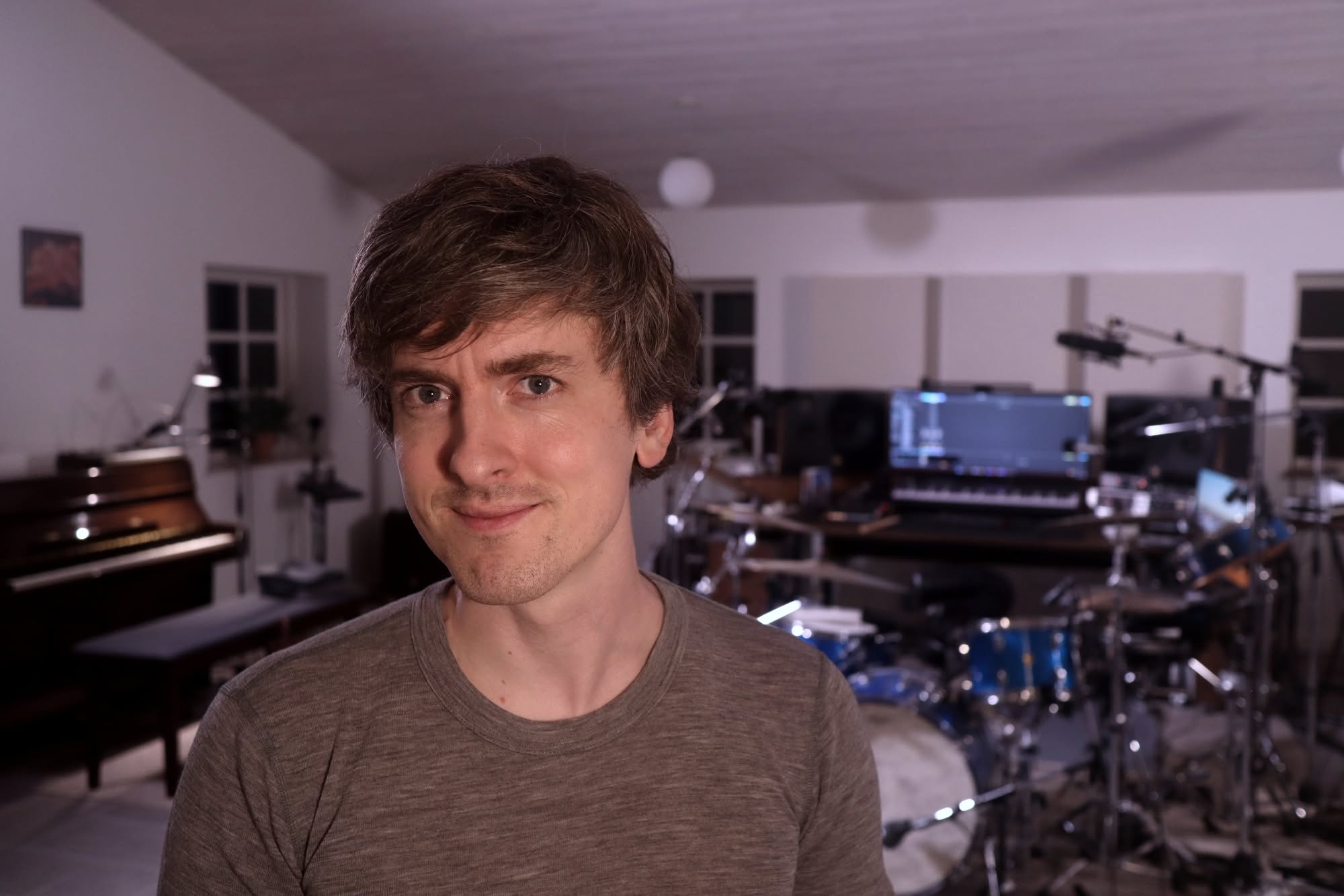 Mikas in his studio, with the drum kit, the piano and the microphones behind him